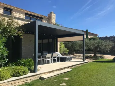 a pavilion with a table and chairs in a garden at Le Clos de Yann in Gordes