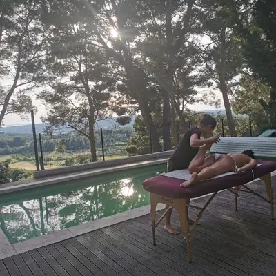 two women sitting on a bench next to a swimming pool at Villa Le Mas des Roches à 15mn airport Marseille in Velaux