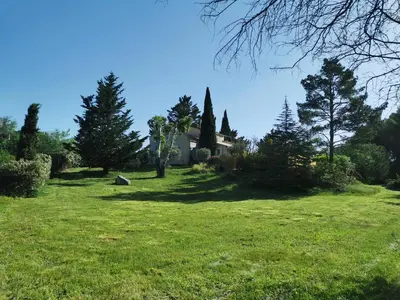a field of grass with a house and trees at Juste en Provence in Saint-Saturnin-les-Apt