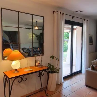 a living room with a table with a lamp and a sliding glass door at les couleurs du sud in Aix-en-Provence