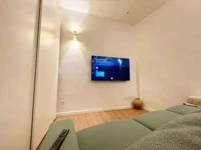 a living room with a couch and a tv on a wall at T2 Cosy - Place des Cardeurs in Aix-en-Provence