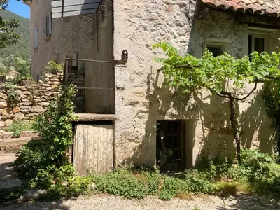 an old stone building with a wooden door and stairs at gîte à Rustrel in Rustrel