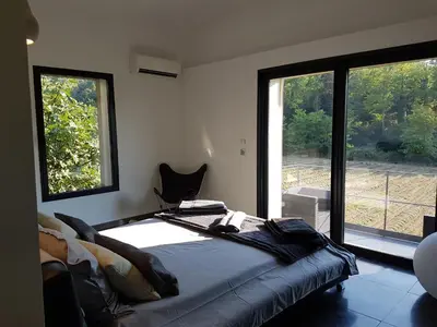 a bedroom with a bed and a large window at Menerbes Luberon maison moderne clim piscine in Ménerbes