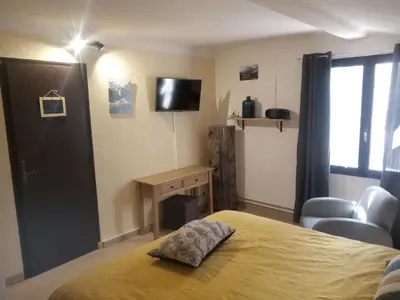 a bedroom with a bed and a desk and a television at Chambres d'hôtes L'Amphitryon 5 CHAMBRES in Villemus