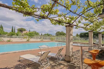 a table and chairs next to a swimming pool at Le Petit Nid in Saint-Rémy-de-Provence