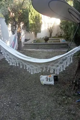 a white hammock in a yard with an umbrella at petite maison avec jardin calme in Le Thor