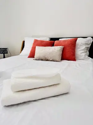 a white bed with white sheets and red pillows at La Villa Rustica in Aix-en-Provence