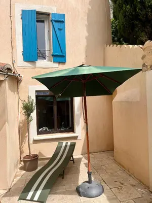 a green umbrella and a bench in front of a building at Charming & medieval village house completely renovated with great exterior and views in Mallemort