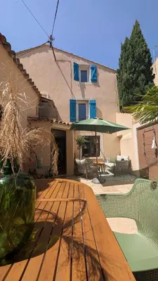 a patio with a wooden table and an umbrella at Charming & medieval village house completely renovated with great exterior and views in Mallemort