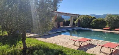 a swimming pool with two red chairs in a yard at La Bastide des Muriers in Gargas