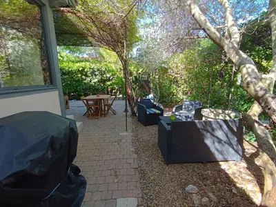 a patio with a table and chairs and a tree at Maison provençale avec piscine partagée in Loriol-du-Comtat
