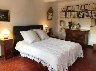 a bedroom with a bed and a dresser with books at La Maison Joly in Ménerbes