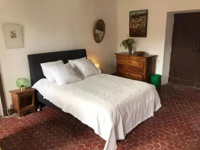 a bedroom with a large bed with a dresser and a mirror at La Maison Joly in Ménerbes