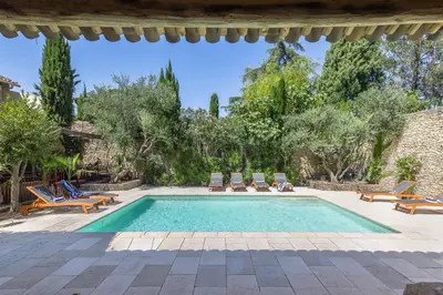 a swimming pool in a yard with chairs and trees at Oasis de Gordes in Gordes