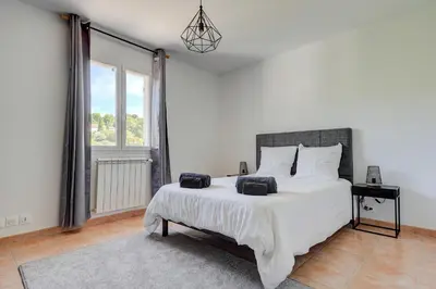 a bedroom with a large white bed and a window at Les Hauts de Provence - Maison avec piscine in Aix-en-Provence