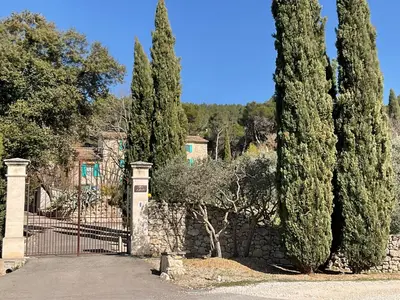 a gate with trees in front of a house at Mas la Floreline in Cheval-Blanc