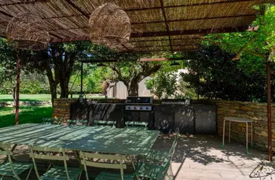 a table and chairs under a straw roof at Maison familiale avec piscine in Aix-en-Provence