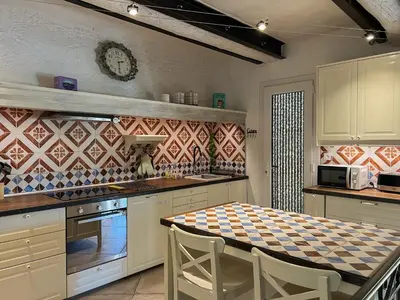 a kitchen with a table and a clock on the wall at Mazet des Balestiés cœur Luberon 120 m2 6 pers avec piscine in Gargas