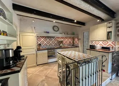 a kitchen with a table in the middle of it at Mazet des Balestiés cœur Luberon 120 m2 6 pers avec piscine in Gargas