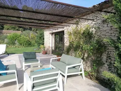 a patio with chairs and a stone wall at Le Mazet d'Alexis in Maubec