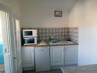 a kitchen with white cabinets and a microwave and a sink at la bastide aux buis avec piscine in Blauvac