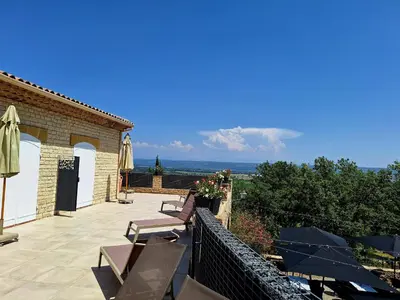 a patio with chairs and tables and an umbrella at Domaine de la Mautanne in Sainte-Tulle