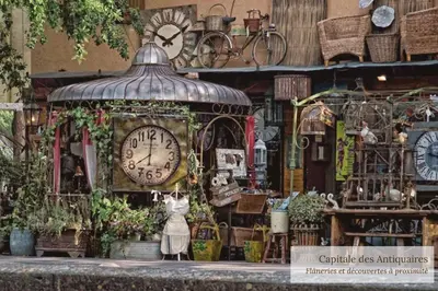 a clock in front of a store with a woman in front at La Maison Bleue in LʼIsle-sur-la-Sorgue