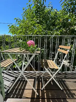a table with two chairs and a pink flower on it at Maison Jasmin in the city center with parking space and terrace in LʼIsle-sur-la-Sorgue