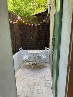 a patio with a table and chairs and a fence at Maison Jasmin in the city center with parking space and terrace in LʼIsle-sur-la-Sorgue