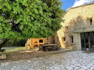 a stone building with a picnic table next to a tree at Bergerie de charme proche Aix en Provence et Lubéron in Rognes