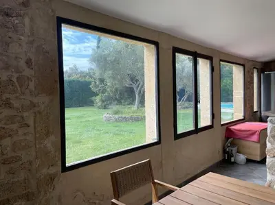 a room with large windows and a table and chairs at Bergerie de charme proche Aix en Provence et Lubéron in Rognes