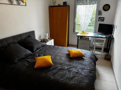 a bedroom with a bed with two yellow pillows on it at Chambre chez habitant résidence piscine in Carpentras