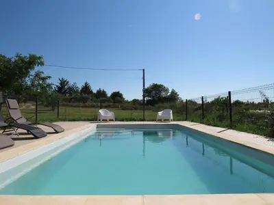 a swimming pool with two lawn chairs next to it at Maison face au Luberon avec piscine - 5 Chambres in Cabrières-dʼAvignon