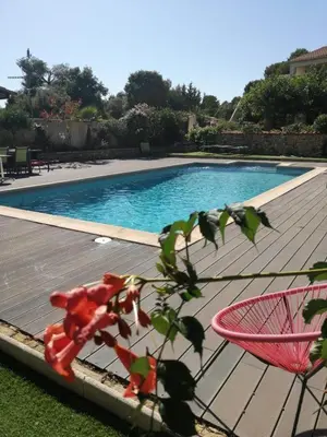 a swimming pool with a pink chair in front of it at Chez Lucho et carole in La Bastidonne