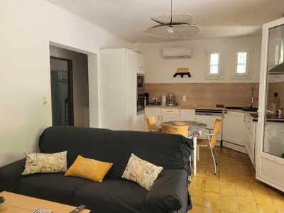 a living room with a black couch and a kitchen at Borie en Provence in Velleron