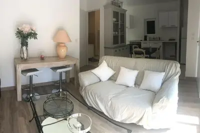 a living room with a white couch and a kitchen at Appartement en bordure de sorgue in LʼIsle-sur-la-Sorgue