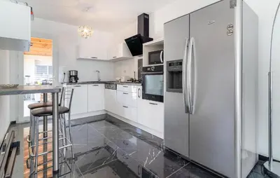 a kitchen with white cabinets and a stainless steel refrigerator at 2 Bedroom Nice Home In Chateaurenard in Châteaurenard