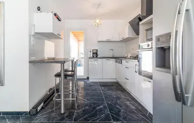 a kitchen with white cabinets and a black tile floor at 2 Bedroom Nice Home In Chateaurenard in Châteaurenard