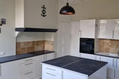 a kitchen with white cabinets and a black counter top at Camargu'Alpilles in Mollégès