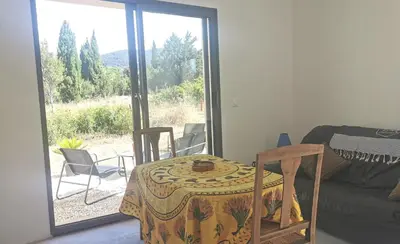 a room with a table and chairs and a large window at Logement au calme à LOURMARIN in Lourmarin