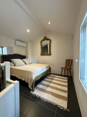 a bedroom with a bed with a mirror and a chair at Les Feuilleres in LʼIsle-sur-la-Sorgue