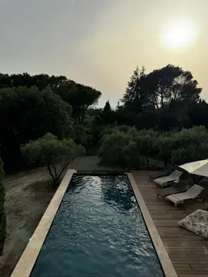 a swimming pool in a yard with a wooden deck at Les Feuilleres in LʼIsle-sur-la-Sorgue