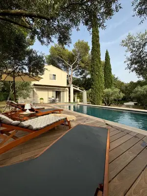 a wooden deck with a bed and a swimming pool at Les Feuilleres in LʼIsle-sur-la-Sorgue