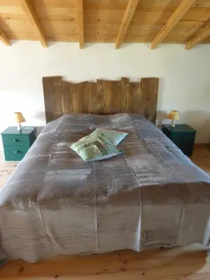 a large bed with a wooden headboard in a bedroom at Le grangeon des Hermas in Sault-de-Vaucluse
