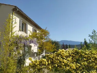 a building with a bunch of yellow flowers in front of it at Villa face au Mont Ventoux avec bassin in Modène