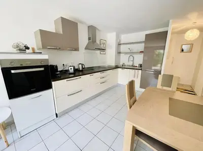a large kitchen with white appliances and a table at Appartement, 1 chambre, jardin privatif in Venelles