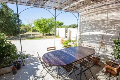 a wooden table and chairs in a covered patio at Maison avec jardin in Saumane-de-Vaucluse