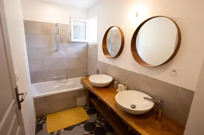 a bathroom with a sink and two mirrors on the wall at Maison avec jardin in Saumane-de-Vaucluse
