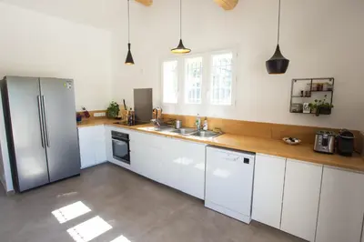 a kitchen with white cabinets and a stainless steel refrigerator at Maison avec jardin in Saumane-de-Vaucluse