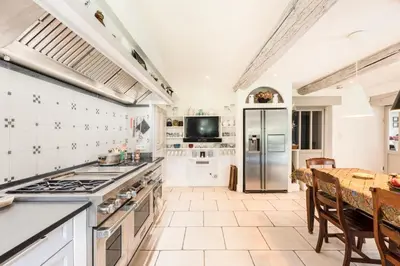 a large kitchen with a table and a refrigerator at Beautiful Provencal Mas with swimming pool in Le Thor